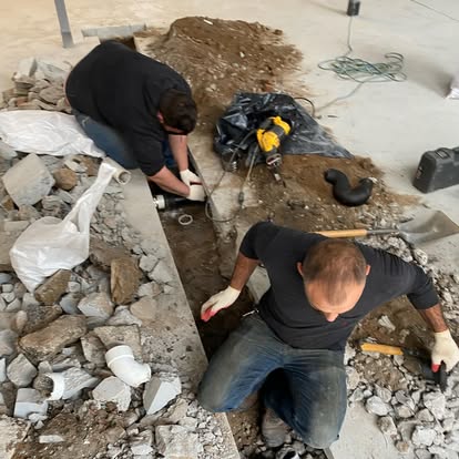 Crew installing new plumbing lines under a concrete floor